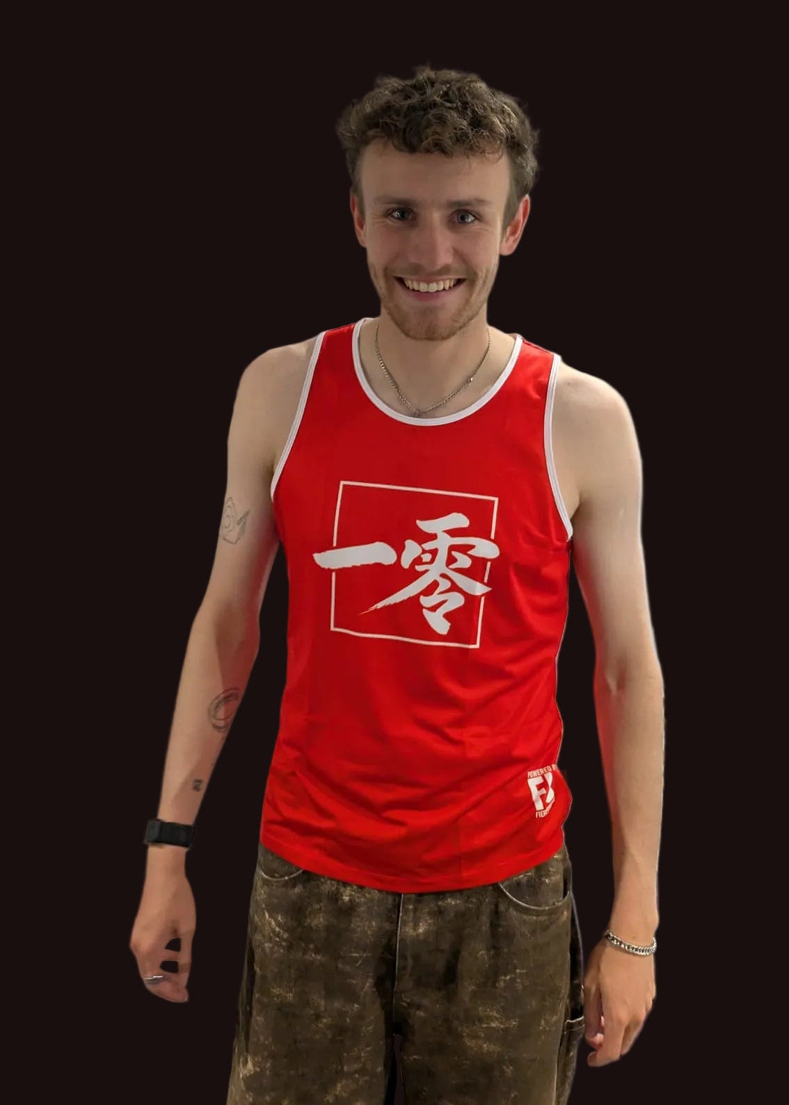 Person wearing a red tank top with white text in a bedroom setting